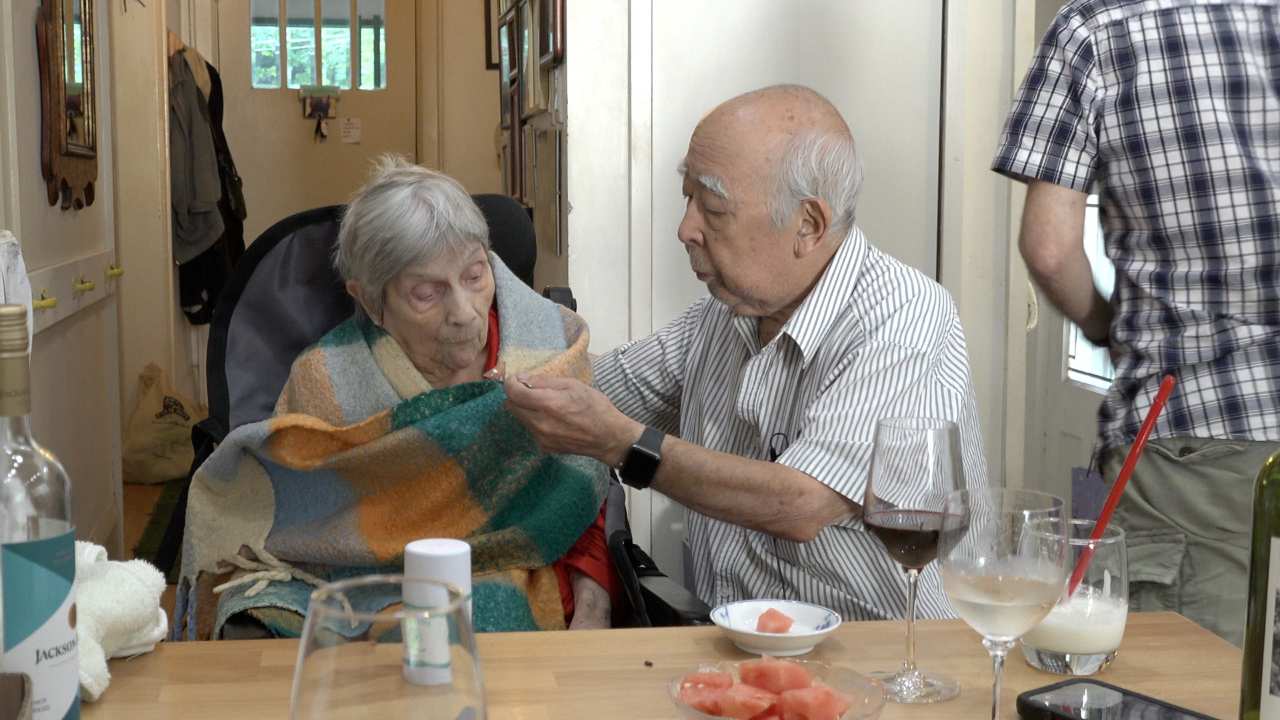 Nobuo Kubota feeding a woman at a house